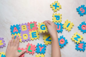 Child playing with alphabet puzzle - literacy and articulation